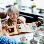 Ältere Menschen teilen Erinnerungen beim Durchblättern eines Fotoalbums in einem gemütlichen Café.