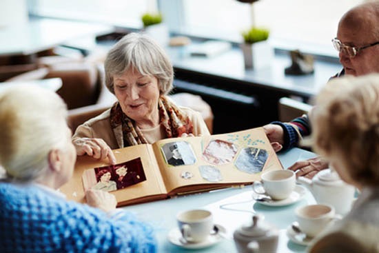 Ältere Menschen teilen Erinnerungen beim Durchblättern eines Fotoalbums in einem gemütlichen Café.