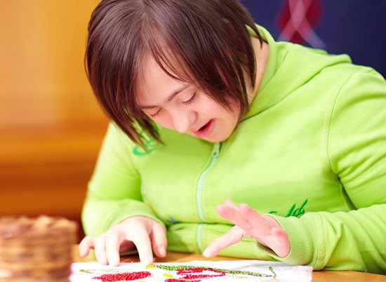 Eine junge Frau mit Down-Syndrom gestaltet mit Freude ein kreatives Kunstprojekt.