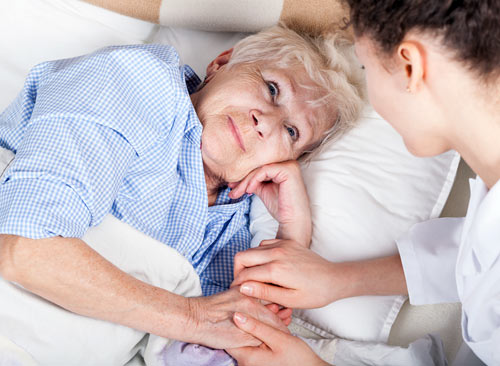 Eine ältere Frau erhält liebevolle Pflege und Unterstützung von einer Betreuerin im Bett.